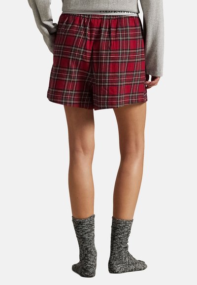 Punaruudulliset shortsit, joissa on joustava vyötärö ja rento istuvuus, yhdistettynä harmaisiin neulottuihin sukkiin. Kangas on sileäpintainen.