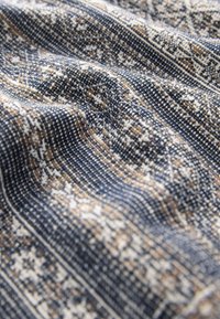 Textilstoff mit einem gewebten Muster in Marineblau, Creme und Braun, mit detaillierten geometrischen Designs und unterschiedlichen Texturen.