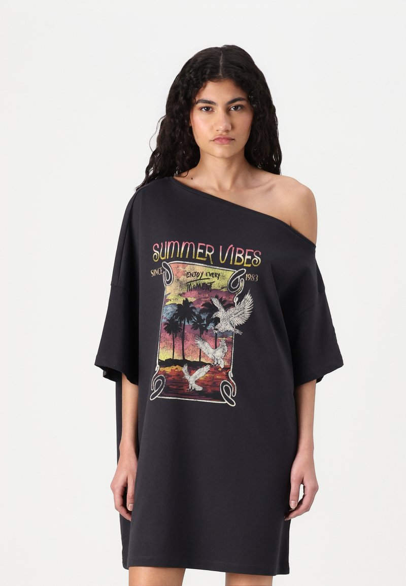 Juodas per didelis T-shirt suknelė, vaizduojanti "Vasariškas nuotaikas" grafiką su palmių ir paukščių motyvais, šiek tiek nuleidžiama pečių linija ir trumpomis rankovėmis.