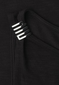 Gros plan sur un tissu noir plié maintenu par une pince métallique argentée brillante comportant quatre barres horizontales.