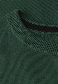 Sweater en tricot vert foncé, avec un col côtelé et une doublure intérieure noire. La texture douce et le gros plan mettent en valeur l'artisanat.