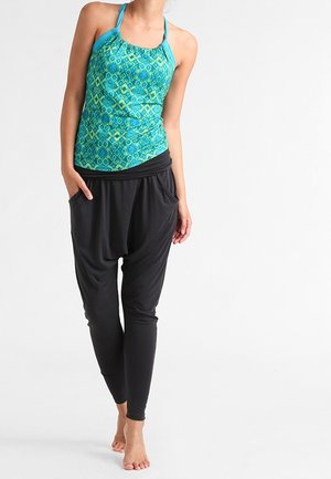 Tyrkysový top bez rukávů se vzorem a s halter ramínky, v kombinaci s černými volnými harem panty. Hladká látka, uvolněný střih a délka zánártní.