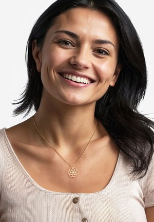 Goldkette mit einem floralen geometrischen Anhänger, getragen zu einem hellen, gerippten Oberteil mit rundem Ausschnitt und Knopfdetails.