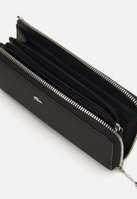 Portefeuille zippé noir en matériau texturé, avec plusieurs compartiments, une fermeture éclair argentée et un petit logo en relief.