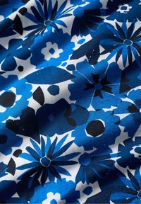 Cotton fabric featuring a blue floral pattern with black and white accents. The design has various flower shapes and uneven textures.