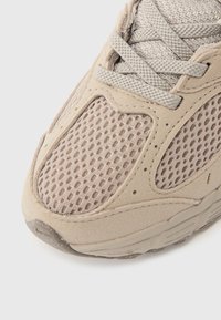 Αθλητικό παπούτσι σε μπεζ χρώμα με επάνω μέρος από δίχτυ και σουέντ, υφή με λεπτομέρειες, κλείσιμο με κορδόνια στρογγυλεμένα και επενδυμένο κολάρο για άνεση.