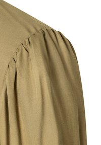 Blouse olive verte avec une texture douce et lisse, présentant des manches bouffantes avec des détails froncés et un design d'épaule légèrement tombante.