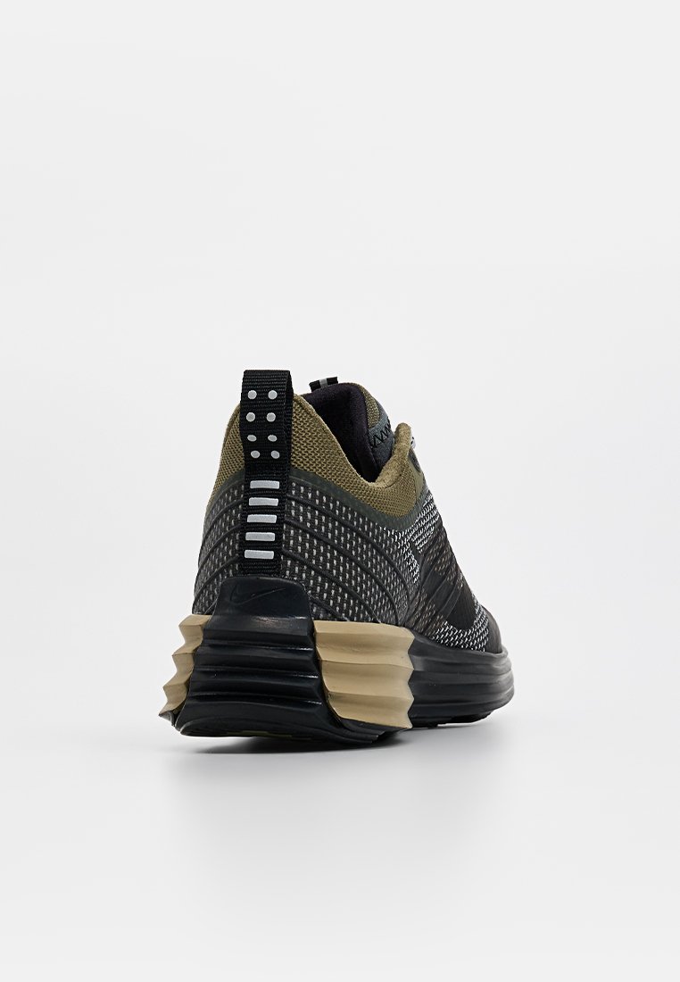 Schwarzer und olivgrüner Sportschuh mit einem strukturierten Design, einer gepolsterten Sohle und einem gemusterten Obermaterial aus Stoff. Verfügt über eine Hinterziehschlaufe.