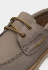 Μπεζ σουέντ παπούτσι σκάφους με ταμπά δερμάτινα κορδόνια, λεπτομερείς ραφές και ανάγλυφο λογότυπο Marc O'Polo στο πλάι.