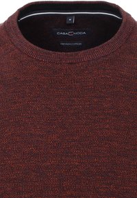 Dieprode breisweater met een ronde hals, gemaakt van premium katoenstof. Kenmerkt zich door gestructureerde steken en een klein etiket bij de kraag.