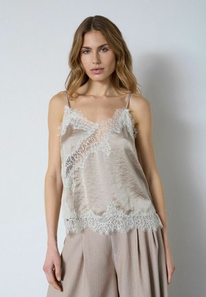 Camisole in seta beige con delicato bordo in pizzo bianco lungo scollo e orlo. Presenta spalline sottili regolabili e una finitura testurizzata.