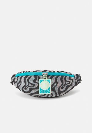 Sac banane à motif abstrait noir et blanc avec une fermeture éclair bleu vif et une étiquette carrée Nike bleu sarcelle et blanche à l'avant.