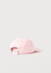 Ανοιχτό ροζ καπέλο μπέιζμπολ με ρυθμιζόμενο μεταλλικό κούμπωμα στο πίσω μέρος, ακουμπισμένο σε απλό ανοιχτό φόντο.