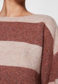 Maglione a righe con ampie bande orizzontali nei colori ruggine e crema, con una finitura morbida e texturizzata e uno scollo a barca.