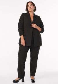 Black suit set featuring a tailored blazer and matching trousers, decorated with subtle white polka dots; finished with a sleek, shiny texture.