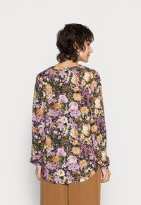 Blusa de mangas longas com um padrão floral multicolorido sobre um fundo preto; apresenta um decote redondo e uma barra curvada.