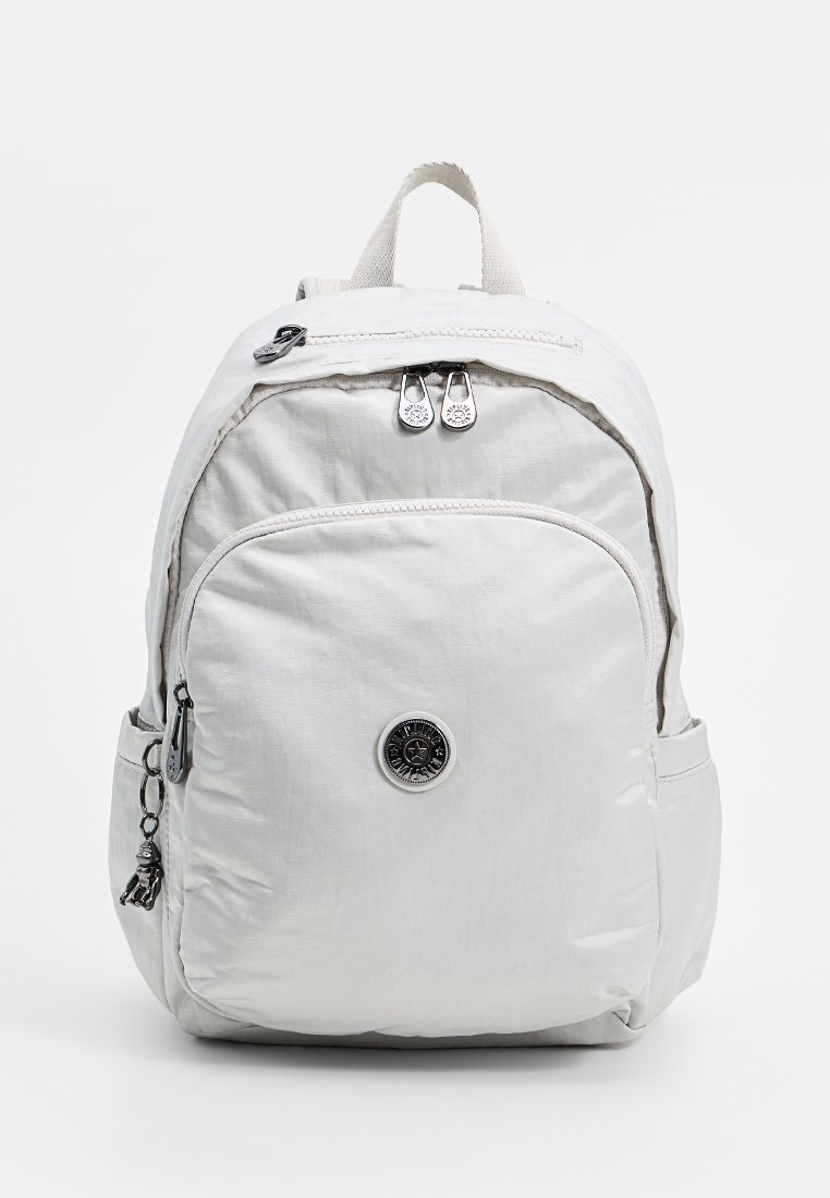 Sac à dos en nylon gris clair avec poche zippée à l'avant, deux zips pour les compartiments principaux, poches latérales, poignée supérieure et écusson rond noir.