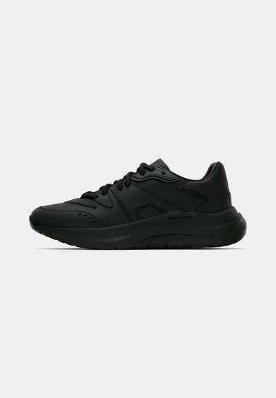 Baskets de sport noires avec une tige synthétique lisse, un bout arrondi, une semelle épaisse et rembourrée, et une fermeture à lacets ; elles présentent des accents de design subtils.