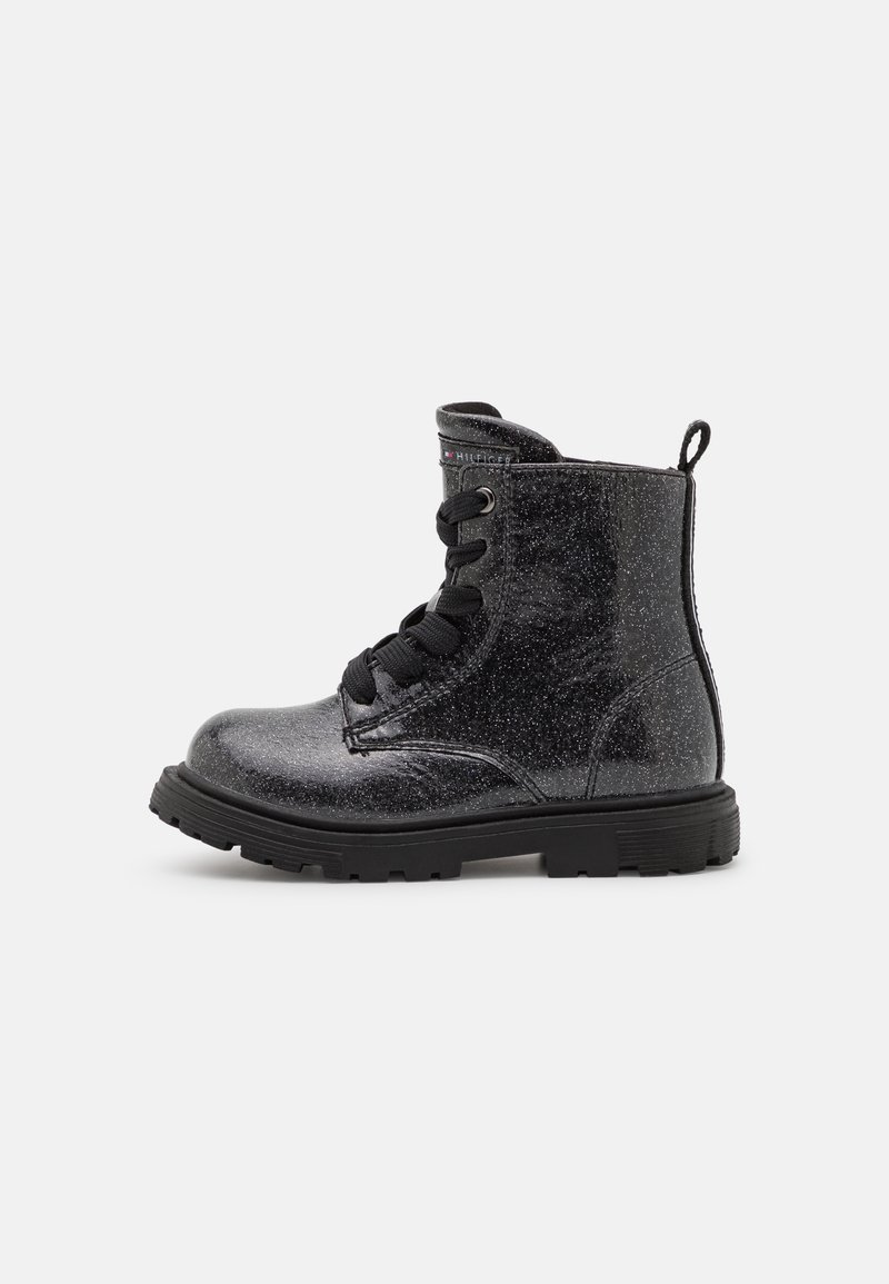Botas de tobillo negras con purpurina, punta redonda, superficie de charol texturizada, seis ojales y cordones negros. Presenta un tirador en forma de bucle en el talón y una suela gruesa.