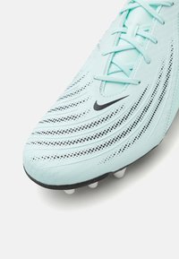 Crampon de football bleu clair avec une finition texturée, logo Nike noir et des détails à motif dynamique. Équipée de crampons moulés blancs sur la semelle.