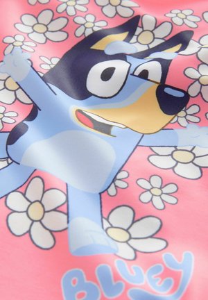 Blue dog character printed on pink fabric surrounded by white daisies; features bright colors and a playful design. Text "BLUEY" included.