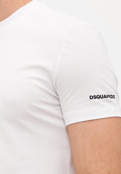 Weißes Baumwoll-T-Shirt mit Rundhalsausschnitt, kurzen Ärmeln und einem schwarzen Logodruck auf dem linken Ärmel. Glatte Textur, figurbetonter Schnitt.