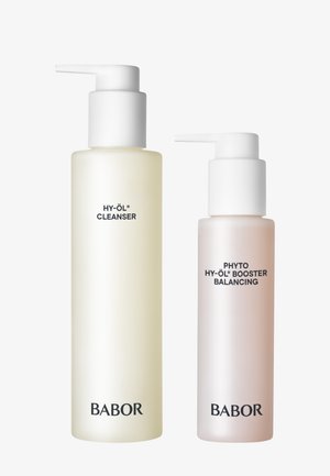 Deux produits de soin de la peau Babor : un nettoyant liquide translucide jaune dans une bouteille haute et élancée, et un booster rose dans une bouteille plus courte et plus large.
