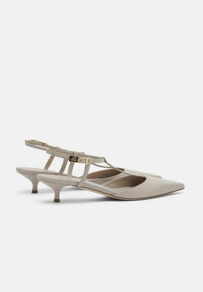 Chaussures à talons kitten slingback en cuir beige avec bouts pointus et boucle dorée sur les brides.