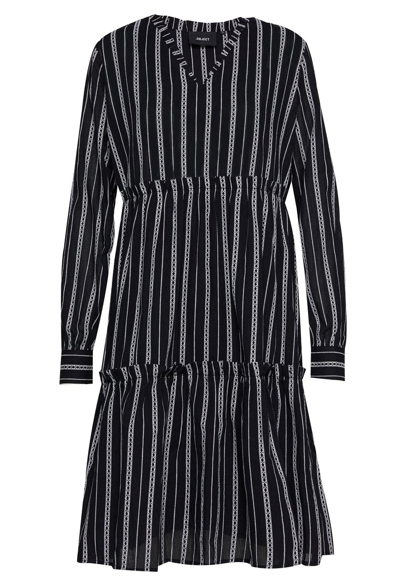 Vestido a rayas blanco y negro con mangas largas, escote en V, cintura fruncida y falda en capas. La tela tiene una textura ligera.