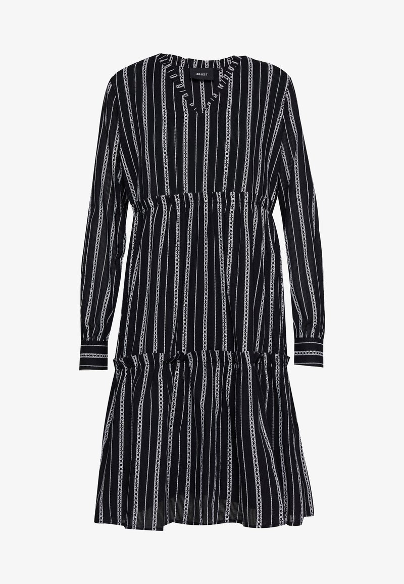 Robe à rayures noires et blanches avec des manches longues, un décolleté en V, une taille froncée et une jupe à volants. Le tissu a une texture légère.