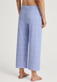 Lichtblauwe, gemusterde broek met wijde pijpen en een elastische tailleband. Bevat bloem- en geometrische ontwerpen in donkerder blauw. Zachte stoftextuur.