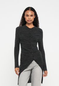 Cardigan longo cinza escuro feito de um tecido macio e texturizado. Apresenta uma frente com botões, uma barra ligeiramente assimétrica e detalhes canelados.