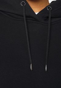 Sudadera negra con cordón ajustable. Fabricada en un material suave, presenta una superficie rica en texturas y puntas metálicas de marca en los cordones.
