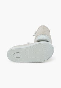 Leichte beigefarbene Canvas-Sneaker mit weißen Schnürsenkeln, runder Zehenpartie, strukturiertem Gummisohle und subtilen Nähten entlang der Kanten.