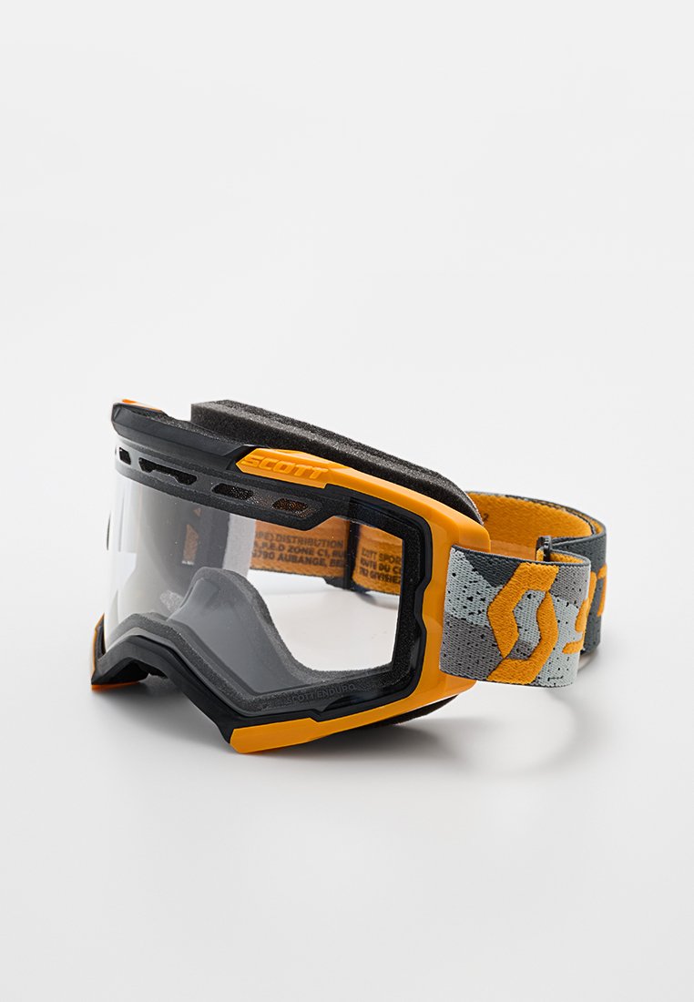 Gafas de motocross Scott en negro y naranja con lente transparente y correa ajustable gris que presenta logotipos naranjas sobre un fondo blanco.