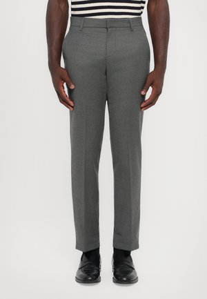 Pantalons gris ajustés à coupe droite, fabriqués à partir d'un tissu texturé. Comprend des passants de ceinture et des poches latérales, associés à des chaussures noires.