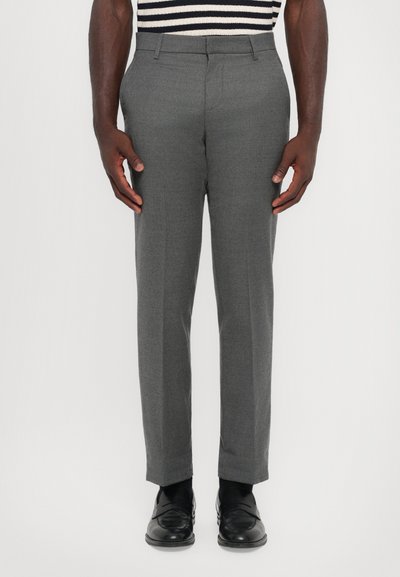 Pantalons gris ajustés à coupe droite, fabriqués à partir d'un tissu texturé. Comprend des passants de ceinture et des poches latérales, associés à des chaussures noires.