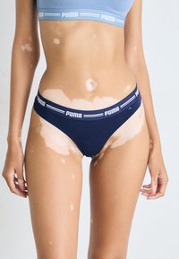 Mornaricki bezšavni bikini s bijelim Puma logotipom na pojasu, izrađen od mekanog materijala, s niskim strukom i glatkim rubovima.