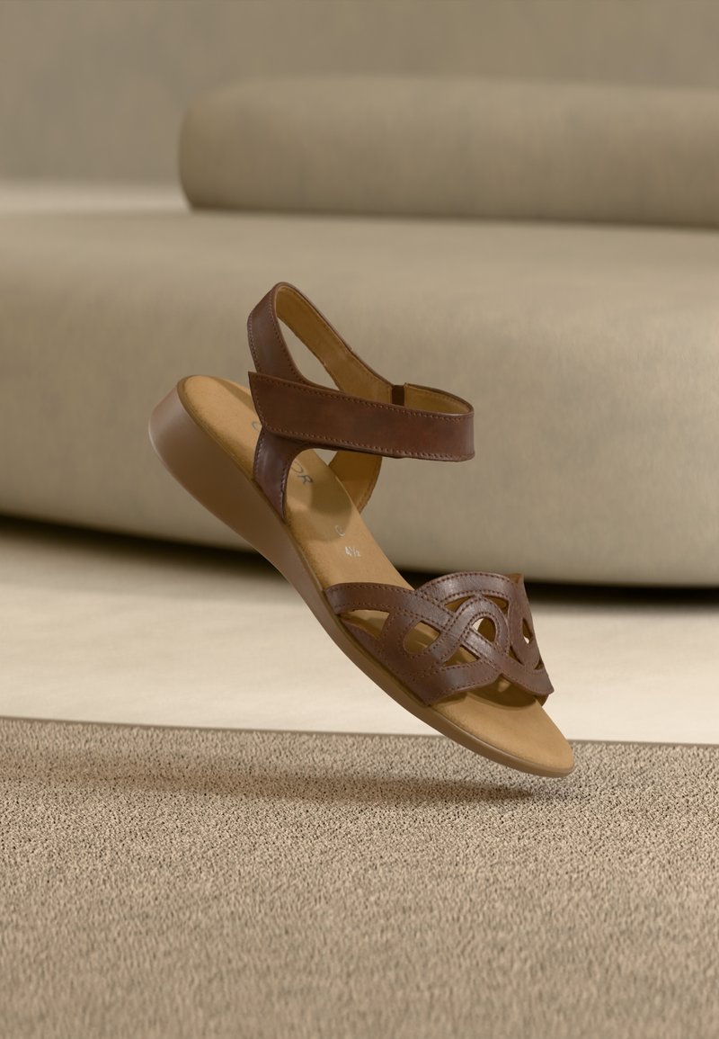 Barna bőrszandál texturált pántdísszel, nyitott orrú stílusban és alacsony sarokkal. Puha talpbetét és bokapánt a kényelemért.
