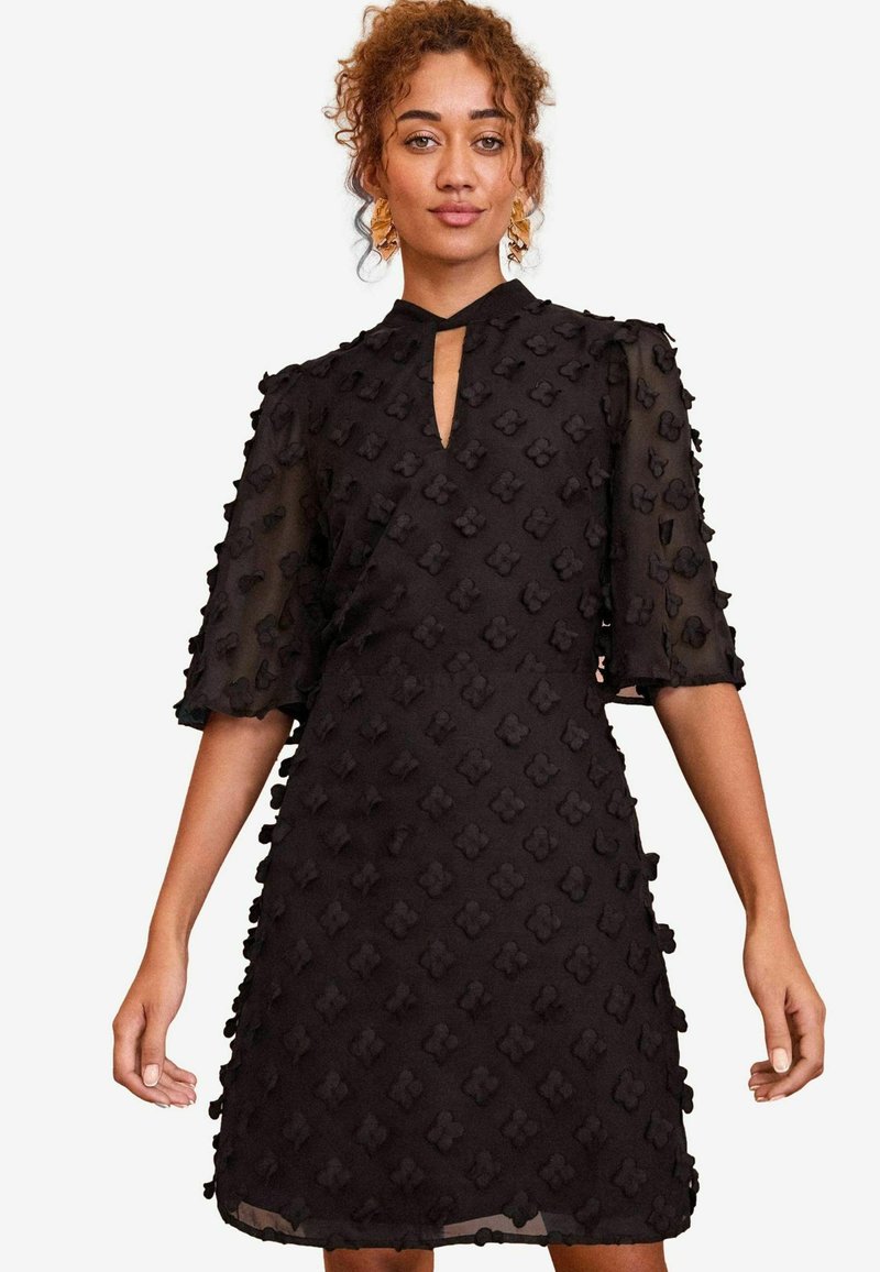 Rochie neagră cu un model floral texturat, decolteu în formă de cheie și mâneci semi-transparente, având un corset ajustat și fustă lejeră.