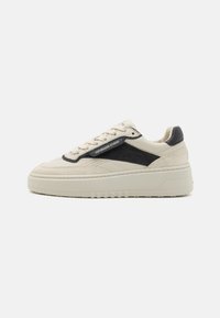 B baskets en cuir beige avec des accents en daim noir, une tige texturée, des détails perforés et une semelle épaisse et chunky pour une hauteur supplémentaire.