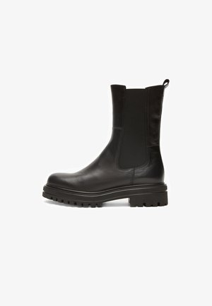Schwarze Lederstiefeletten mit elastischen Seitenpaneelen, abgerundetem Zehenbereich und einer dicken, strukturierten Gummisohle mit tiefen Rillen für besseren Halt.