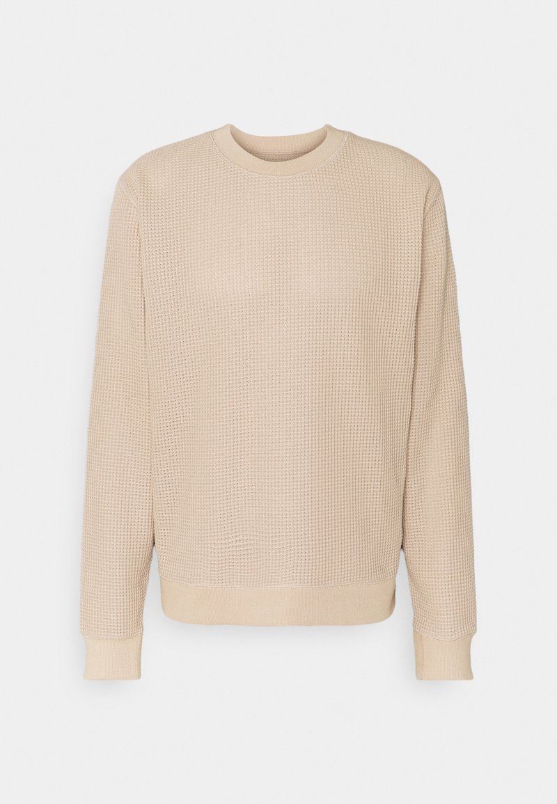 Beżowa dzianinowa bluza z teksturowanym wzorem, okrągłym dekoltem oraz ściągaczami na mankietach i u dołu. Prosty, luźny krój.