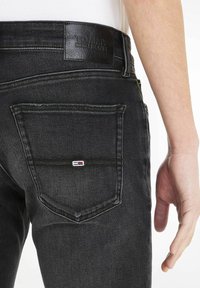 Czarne dżinsy z denimu z skórzaną naszywką z napisem "TOMMY JEANS", z dwoma tylnymi kieszeniami i kontrastowymi detalami przeszyć.