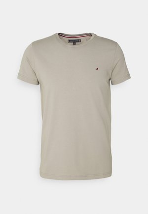 Short-sleeve crew neck t-shirt in light beige cotton blend, featuring a small logo in red, white, and blue on the chest, with stitched hems.