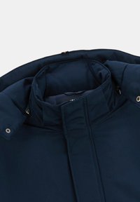 Col de veste bleu marine avec un col montant, doté d'une fermeture éclair à l'avant et de boutons-pression. Tissu lisse avec un design structuré.