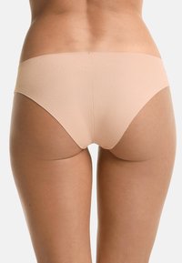 Naadloze, lage slip van zacht nude materiaal, ontworpen voor comfort. Fluweelachtige textuur met minimale bedekking aan de achterkant, geen zichtbare naden.