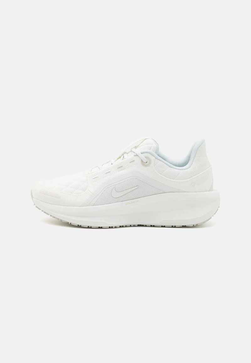 White athletic shoe with a textured mesh upper, padded collar, and a thick sole. Features light blue accents and a reflective logo.