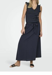 Marineblau gestreiftes Oberteil mit rüschensatz Ärmeln, kombiniert mit einem langen, einfarbigen Marineblau-Rock mit einer Gürteldetail. Tragen mit schwarzen Sandalen.