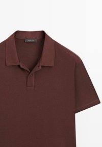 Brun kortærmet polo med to-knaps stolpelukning og krave, mærket Massimo Dutti, lagt fladt på en hvid baggrund.